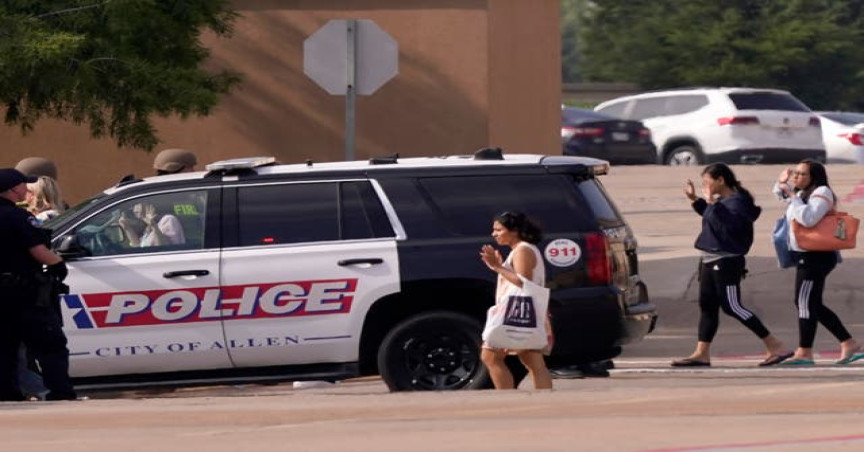 People raise their hands as they leave a shopping center after a shooting, Saturday, May 6, 2023, in Allen, Texas
