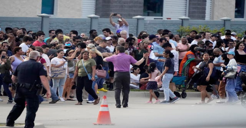 People gather across the street from a shopping centre after a shooting on Saturday, May 6, 2023, in Allen, Texas