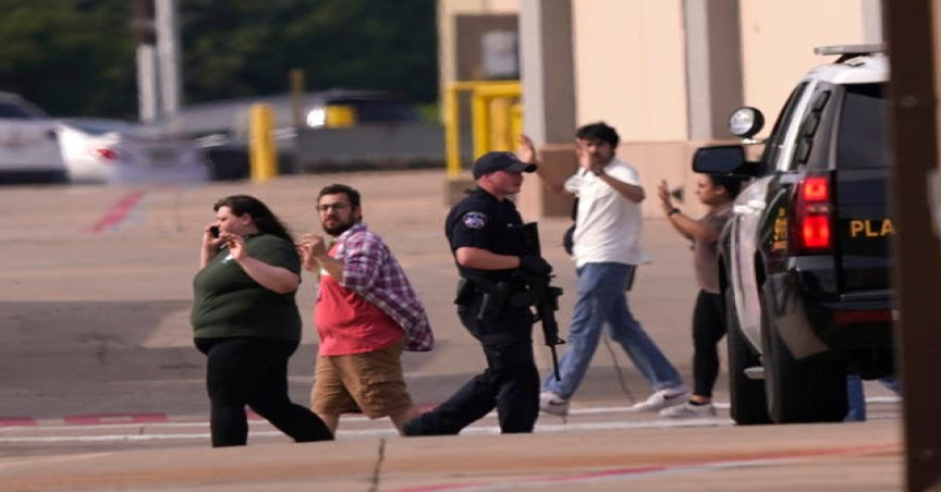 People raise their hands as they leave a shopping centre following reports of a shooting in Allen, Texas