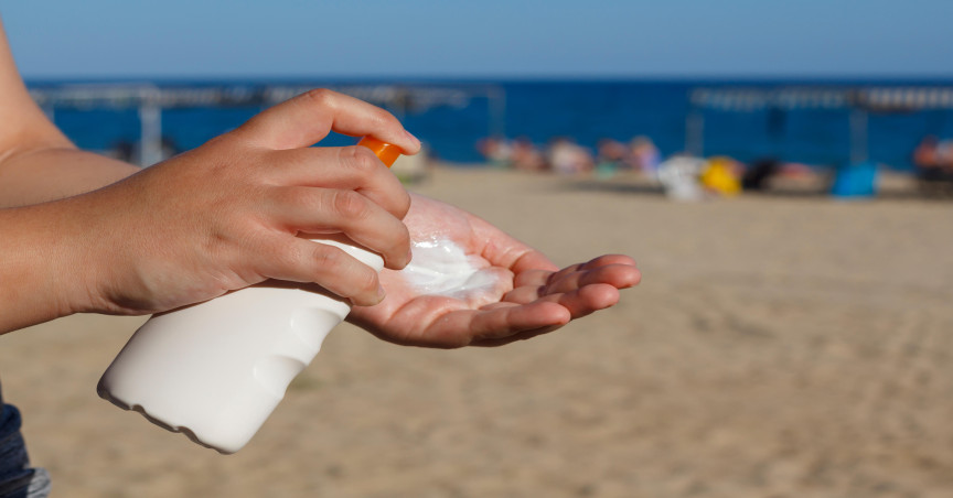 spraying sunscreen onto palm of hand