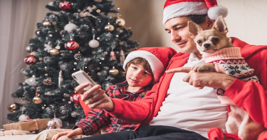 Dad and young son at home together at Christmas, looking at a phone