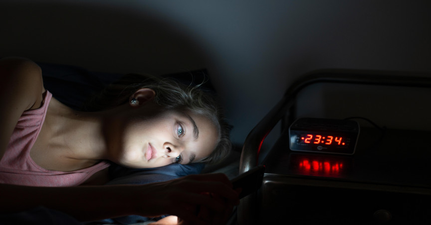 Young girl in bed late at night using her smartphone. Mobile or social media addiction