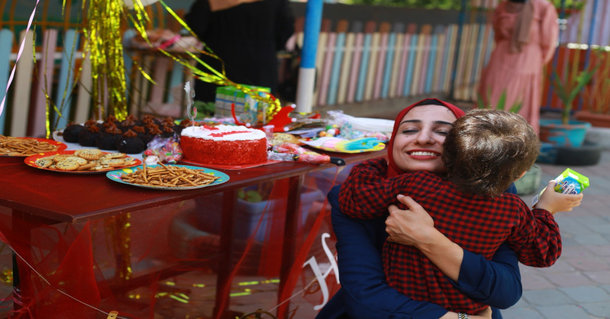 Israa and Marlin hugging in front of a table at Marlin's third birthday party 